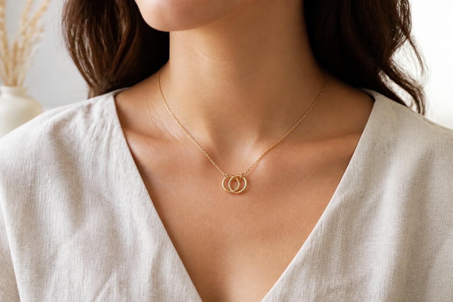 A rose gold Eternal Necklace worn close to the collarbone with a simple white blouse